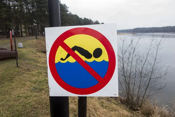 "no bathing or swimming" sign set on the shore of a lake covered — Stock Photo, Image