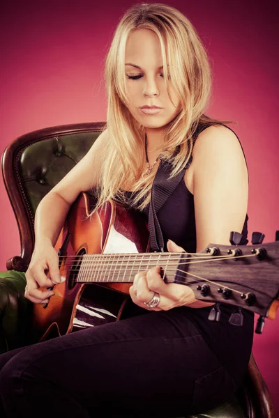 金发碧眼的女人坐在和弹吉他 — 图库照片
