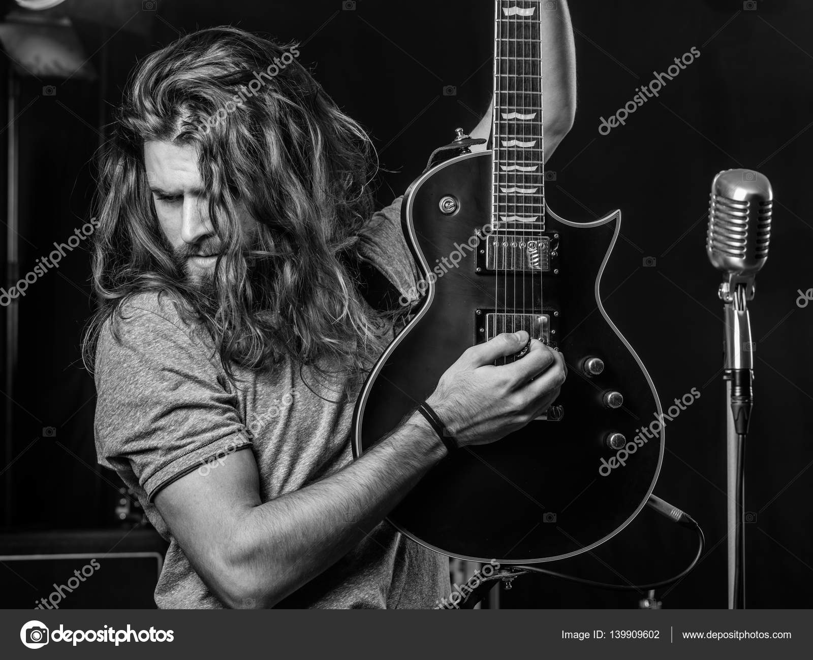 Attractive man playing electric guitar on stag Stock Photo by ©sumners