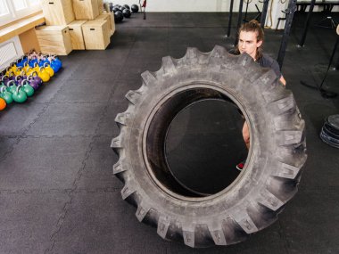 Spor salonunda bir traktör lastiği ile egzersiz adam