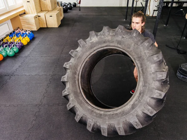 Spor salonunda bir traktör lastiği ile egzersiz adam — Stok fotoğraf