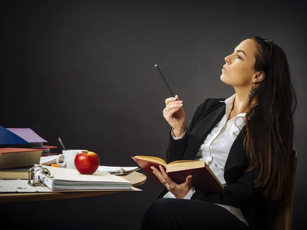 Belle enseignante assise à son bureau pensant — Photo