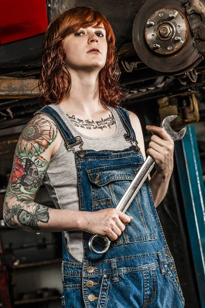 Beautiful redhead mechanic fixing brakes — Stock Photo, Image
