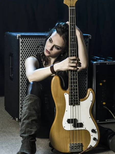 Beautiful woman bass player sitting with her amp — Stock Photo, Image