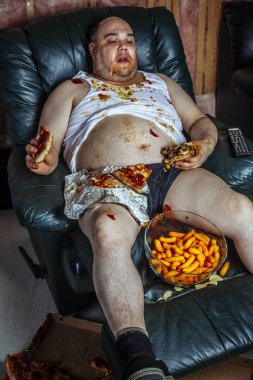 Abur cubur yemek ve televizyon izlerken şişman adam