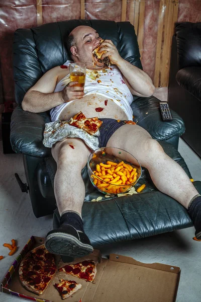 Grasso uomo mangiare e guardare la televisione — Foto Stock