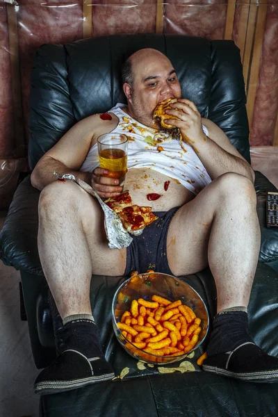 Overweight man eating and watching TV — Stock Photo, Image