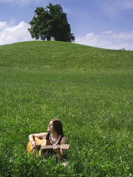 Woman playing guitar in large field — Stock Photo, Image