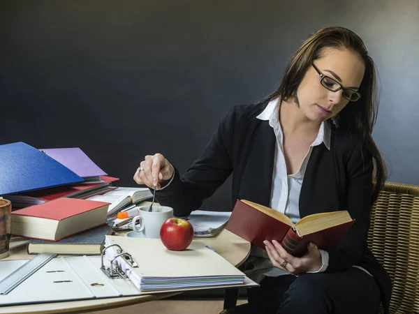 Belle enseignante assise à son bureau lisant — Photo