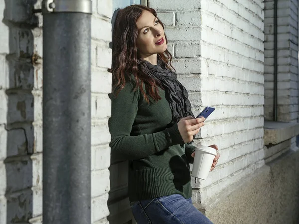 Vrouw controleert haar berichten en drinkt koffie buiten — Stockfoto