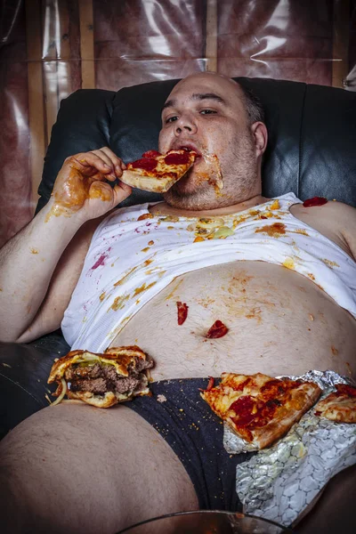 Fat man eating junk food and watching television — Stock Photo, Image