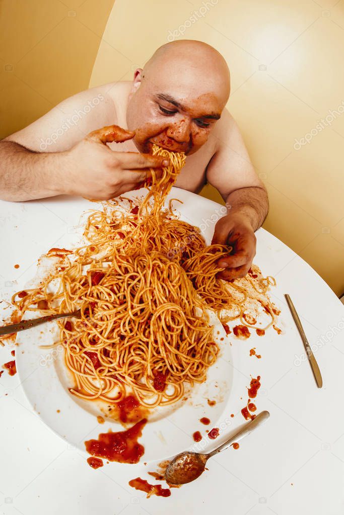 Overweight bald man eating messy spaghetti