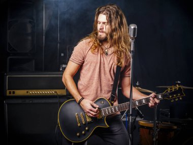 Genç adam sahnede elektro gitar çalıyor.