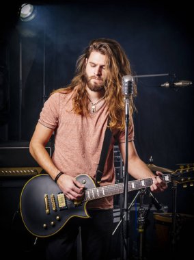 Genç adam sahnede elektro gitar çalıyor.