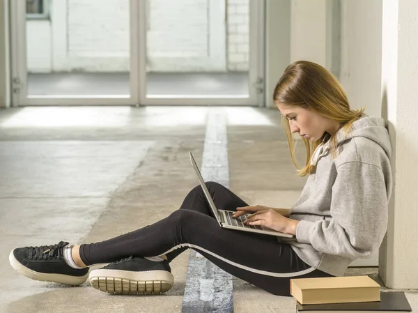 Young student working on her laptop in school hallway — Stock Photo, Image