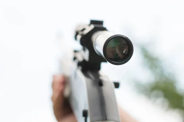 Gun i händerna på den himmel bakgrunden — Stockfoto