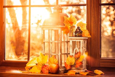 Vintage lanterns, autumn leaves and red apple in evening sun shi clipart