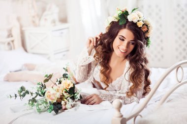 Seksi gelin buketi sabah bir yatakta yalan ile beyaz geceliği ve çelenk giymiş. Yatay. Serbest resim.