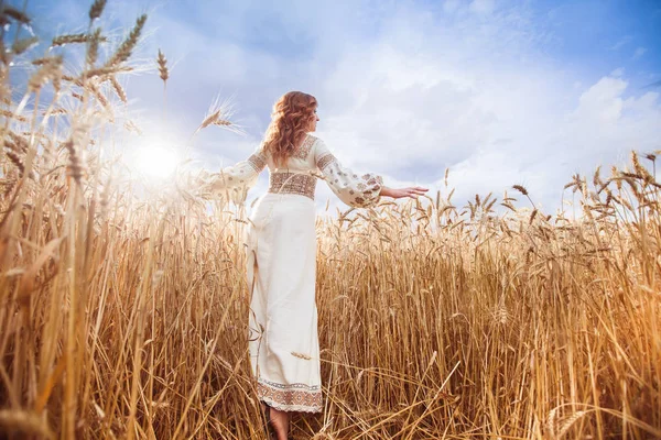 Красива жінка, одягнена у вишиту блузку на пшеничному полі — стокове фото