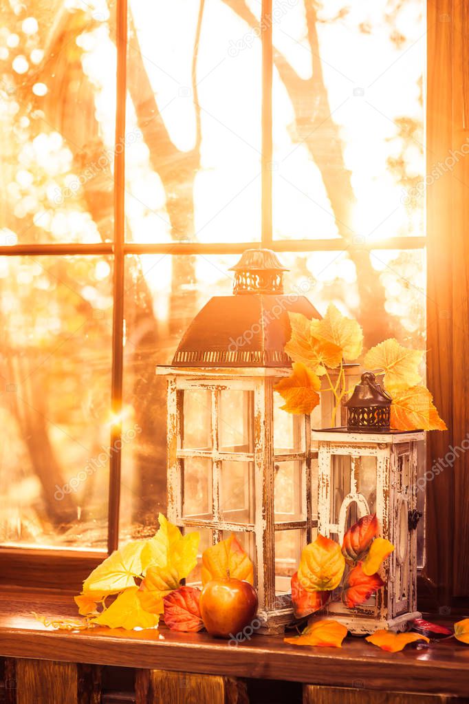 Vintage lanterns, autumn leaves and red apple in evening sun shi