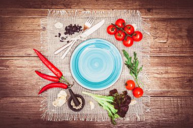 Taze domates, biber ve diğer baharatlar ve otlar ahşap masa ve bez peçete merkezinde modern turkuaz plaka çevresinde. Üstten Görünüm. Metniniz için boş yer. Yatay.