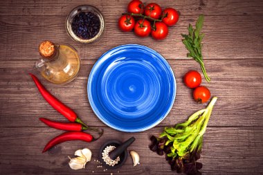 Taze domates, biber ve diğer baharatlar ve otlar ahşap masa ve bez peçete merkezinde modern mavi plaka çevresinde. Üstten Görünüm. Metniniz için boş yer. Yakın çekim.