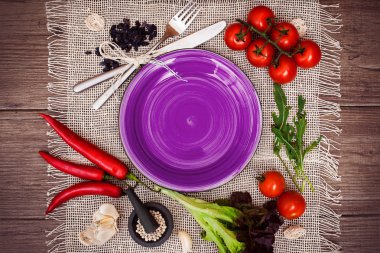 Taze domates, biber ve diğer baharatlar ve otlar ahşap masa ve bez peçete merkezinde modern mor plaka çevresinde. Üstten Görünüm. Metniniz için boş yer. Yakın çekim.