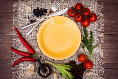 Taze domates, biber ve diğer baharatlar ve otlar ahşap masa ve bez peçete merkezinde modern sarı plaka çevresinde. Üstten Görünüm. Metniniz için boş yer. Yakın çekim.