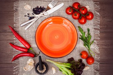 Taze domates, biber ve diğer baharatlar ve otlar ahşap masa ve bez peçete merkezinde modern turuncu plaka çevresinde. Üstten Görünüm. Metniniz için boş yer. Yakın çekim.