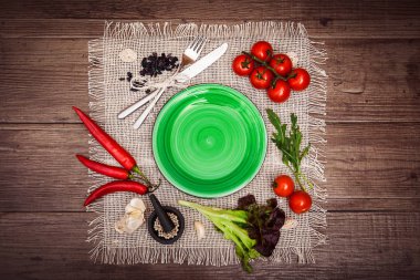 Taze domates, biber ve diğer baharatlar ve otlar ahşap masa ve bez peçete merkezinde modern yeşil plaka çevresinde. Üstten Görünüm. Metniniz için boş yer. Yatay.