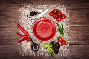 Taze domates, biber ve diğer baharatlar ve otlar ahşap masa ve bez peçete merkezinde modern kırmızı plaka çevresinde. Üstten Görünüm. Metniniz için boş yer. Yatay.