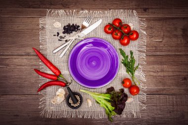 Taze domates, biber ve diğer baharatlar ve otlar ahşap masa ve bez peçete merkezinde modern mor plaka çevresinde. Üstten Görünüm. Metniniz için boş yer. Yatay.