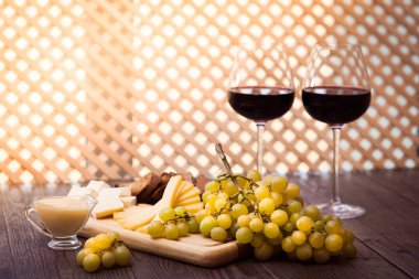 Peynir, kahverengi ekmek, iki bardak kırmızı şarap. Yatay.