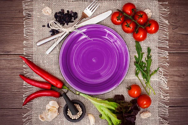 Taze domates, biber ve diğer baharatlar ve otlar ahşap masa ve bez peçete merkezinde modern mor plaka çevresinde. Üstten Görünüm. Metniniz için boş yer. Yakın çekim.