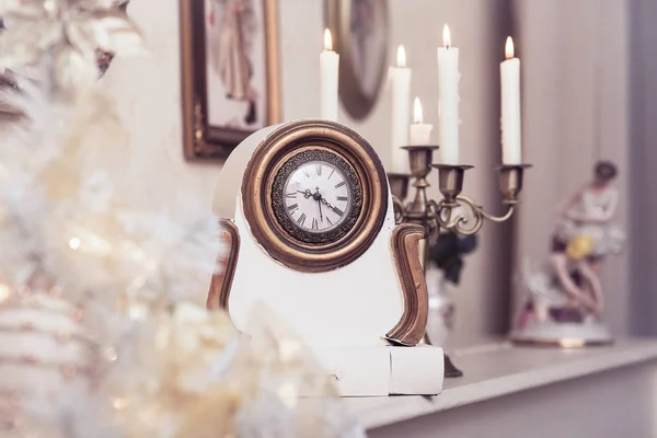 White vintage clock at the burning candles background. — Stock Photo, Image