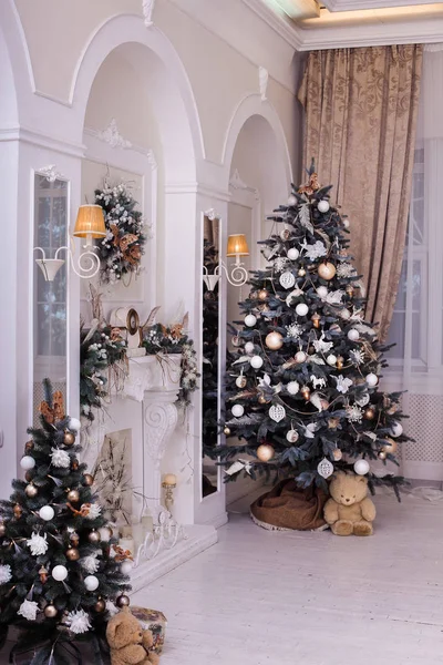 Decorated Christmas trees near mirrors, fireplace under arches — Stock Photo, Image