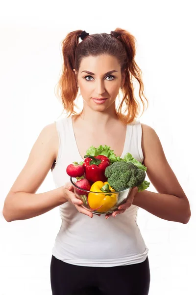 Pelirroja chica caucásica sosteniendo vasos tazón con papas fritas pimientos dulces, rábano, brócoli y lechuga — Foto de Stock