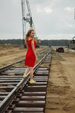 Demiryolunda dans eden kırmızı elbiseli genç Asyalı kadın.