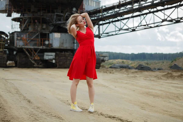Kırmızı elbiseli güzel Asyalı kadın dev sanayi arka planında poz veriyor.