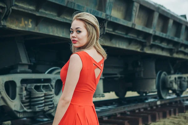 Kırmızı elbiseli Asyalı genç kadın kargo vagonunda poz veriyor.