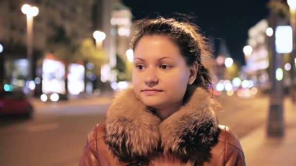 Sevimli kız gülümsüyor gece şehrin arka planı — Stok video