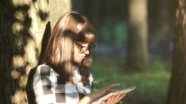 Девушка отдыхает в парке с планшетным компьютером — стоковое видео