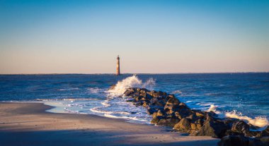 break water and lighthouse in Folly beach clipart