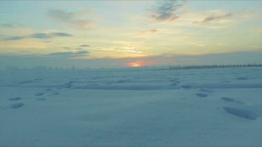 Gün batımı uçan kar kırsal kesimde insan ve hayvan izleri olan bir alanın üzerinde. Son derece düşük uçuş. Drone kullanılan, 30 kare/sn