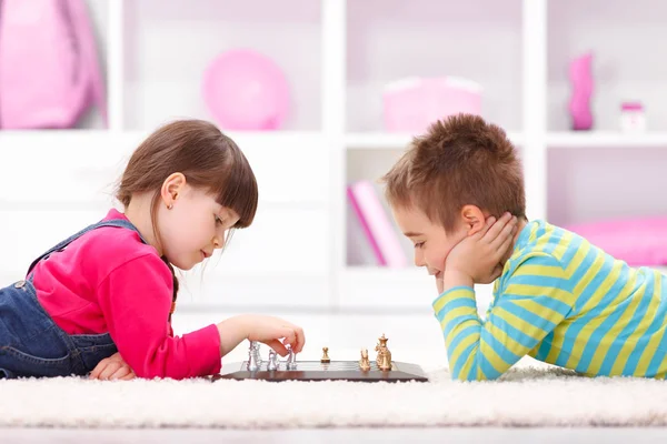 Malou holčičku a chlapce hrát šachy — Stock fotografie