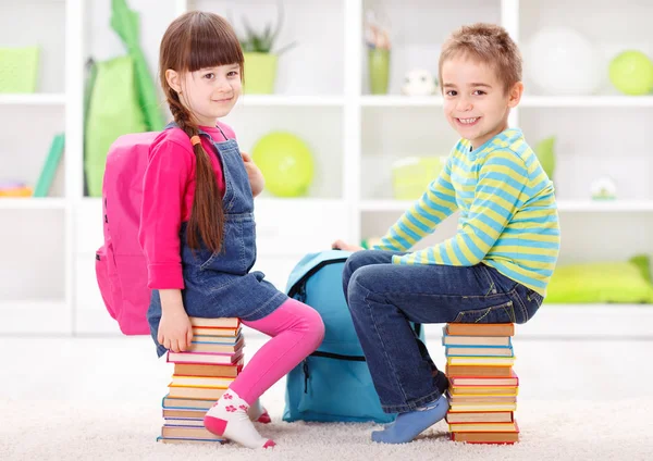 Petits élèves assis sur des piles de livres — Photo