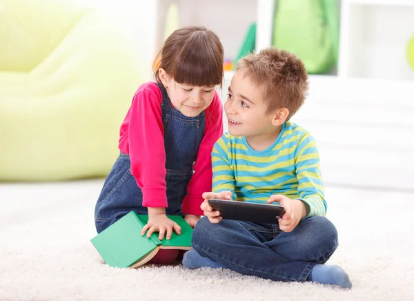 Mały chłopiec i dziewczynka gra lub odczytu z tabletu — Zdjęcie stockowe