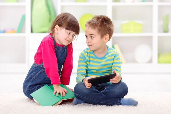Menino e menina brincando ou lendo de tablet — Fotografia de Stock