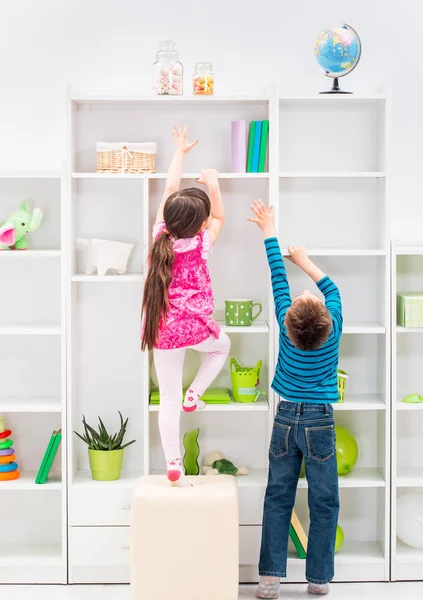 Les enfants essayant d'atteindre des bonbons Image En Vente