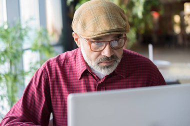 Halka açık bir yerde bilgisayar kullanan yetişkin Hipster adam